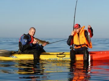 two anglers on a kayak with fish