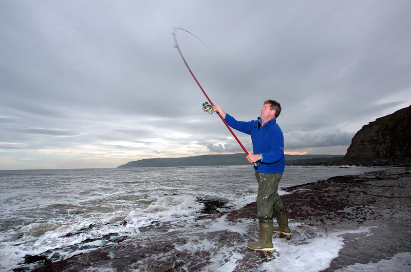 A sea angler reeling in with a fixed spool reel that has been